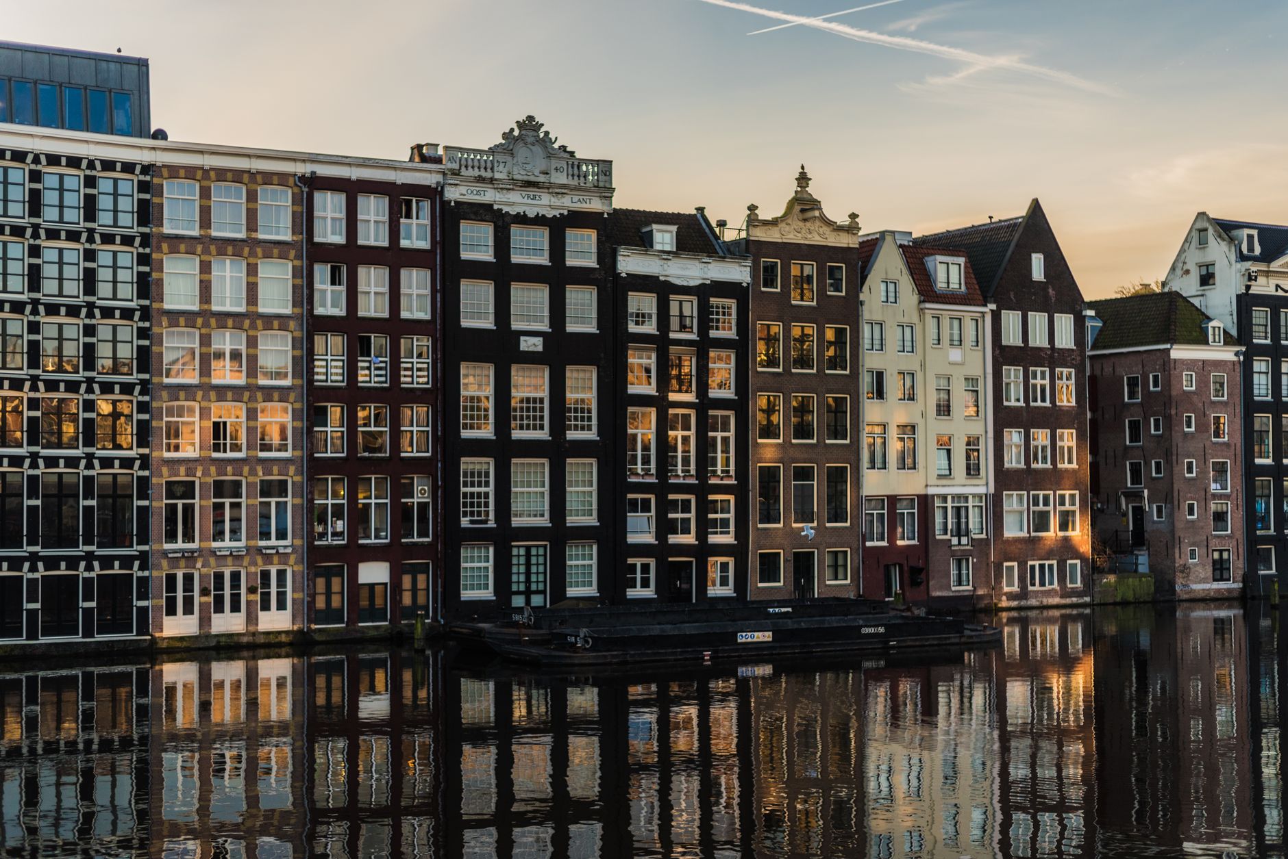 Traditional canal houses reflected in the water at golden hour in Amsterdam, KLM's home city